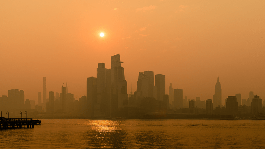 Sunrise over the New York City skyline, obscured and tinted orange by smoke from Canadian wildfires. 