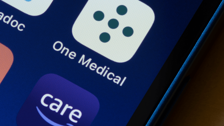 A close-up of mobile applications on a smart phone screen. The icon in the middle of the image is for One Medical; below it is the Amazon Care icon. There are two other icons to the left, but they are not fully visible. 